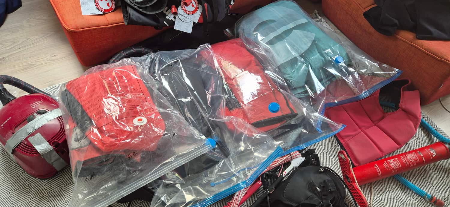 Multiple kitesurfing kites fully flattened and compressed inside plastic storage vacuum bags